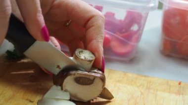 Kız dondurmak için sebzeleri kesip dondurucuya koyuyor. Farklı donmuş sebzeler, çeşitli taze sebzelerin arasında bir yemek masasının üzerinde kısmen kayganlaştırılmış.