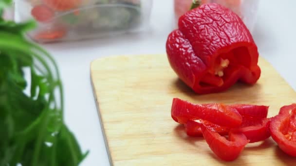 La muchacha corta hortalizas congelar, los ponen en el congelador para el almacenaje. Diferentes verduras congeladas en un plato blanco entre varias verduras frescas parcialmente deslizadas en la tabla de cortar en una mesa de cocina — Vídeos de Stock