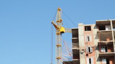 İnşaat halindeki birçok uzun bina ve mavi gökyüzü altında vinçlerle çalışmak.