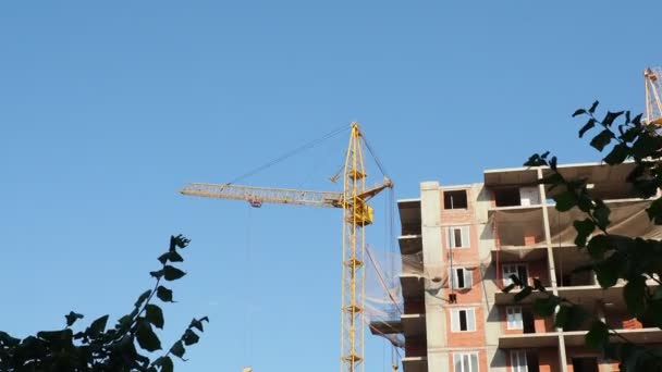 Werken op plaats met veel hoge gebouwen in aanbouw en kranen onder een blauwe hemel — Stockvideo