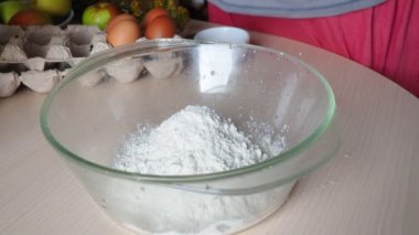 Kadın eli masanda hamur yoğuruyor una yumurta ekliyor kabartma tozu ve şeker ekliyor.