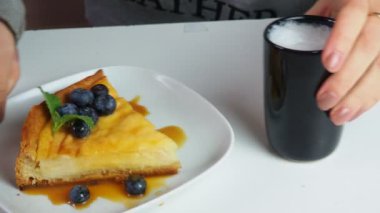 Kapalı kapılar ardında kremalı mascarpone peynirli kek yaban mersinli ve kış meyveli kek yiyen bir kız. New York peynirli keki. Kapatın. Noel tatlısı. Sağlıklı yiyecekler. Yaratıcı atmosfer dekorasyonu.