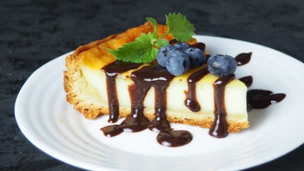 Skiva av läcker cheesecake med bär frukt på ett svart bord. — Stockvideo