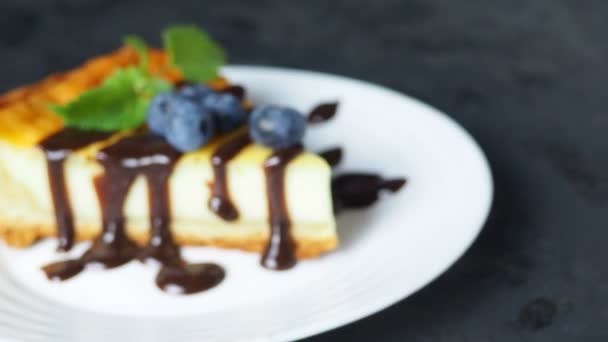 黒テーブルの上にベリーフルーツとおいしいチーズケーキのスライス. — ストック動画