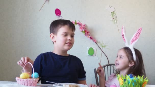 Junge und Mädchen bereiten lachend Plätzchen für Ostern vor. Spaß bei der Ostereiersuche. Junge und Mädchen tragen Hasenohren und bemalen Eier. bunte Eier. — Stockvideo