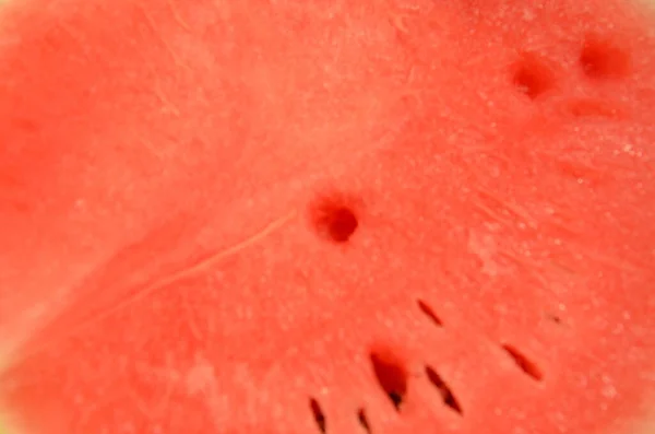 Vattenmelon på ett hackblock. Händerna håller vattenmelon. En hand som håller en kniv. Vattenmelonen skars och separerades. Vattenmelon är röd, grön och fuktig. Vattenmelon ser läcker ut. — Stockfoto
