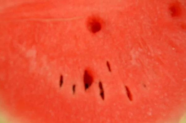 Vattenmelon på ett hackblock. Händerna håller vattenmelon. En hand som håller en kniv. Vattenmelonen skars och separerades. Vattenmelon är röd, grön och fuktig. Vattenmelon ser läcker ut. — Stockfoto