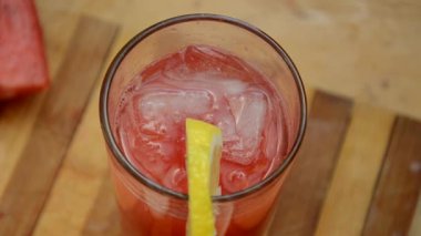 Renkli tropikal taze karpuz smoothie yaz içecekleri ahşap masa arkasındaki bardaklarda. Yeşil yaprakların arka planında sümüklü karpuz pamuğu serinletiyor. Konsept: