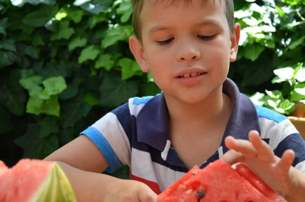 Funny kid eating watermelon outdoors in summer park, focus on eyes. Child, baby, healthy food — Stock Photo, Image
