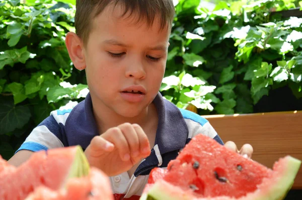 Funny kid eating watermelon outdoors in summer park, focus on eyes. Child, baby, healthy food — Stock Photo, Image