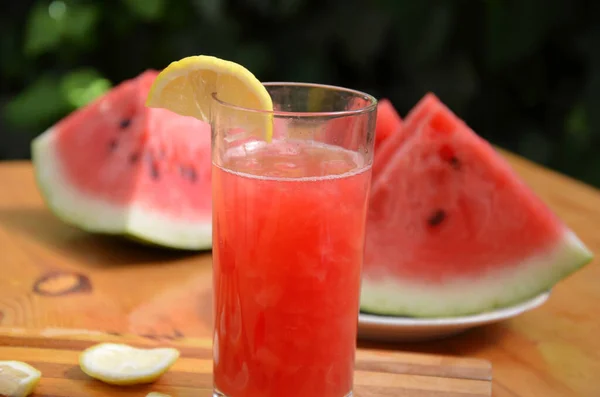 Színes trópusi friss görögdinnye smoothie nyári italok a poharak fa asztal háttér. Frissítő görögdinnye coteil nyálkás háttér zöld lombozat. A következők fogalma: — Stock Fotó