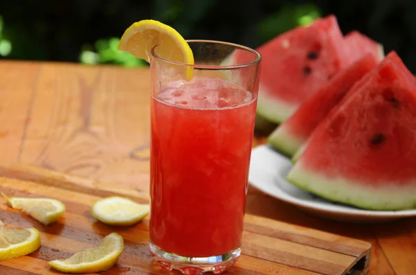 Bunte tropische, frische Wassermelonen-Smoothie-Sommergetränke in den Gläsern auf Holztischhintergrund. Erfrischende Wassermelone mit Zitronensaft vor grünem Laub. Das Konzept der — Stockfoto