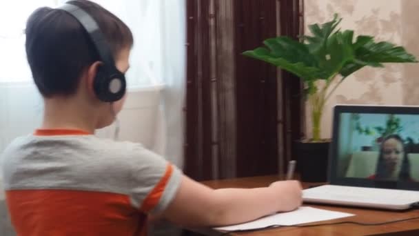 Un niño preadolescente inteligente sentado en la mesa, escribiendo tareas o preparándose para el examen. Adolescente usando la computadora portátil para estudiar. Estudiante, Escuela, Remoto, Aprendizaje en línea, Nuevo normal, Aprendizaje basado en el hogar. — Vídeo de stock