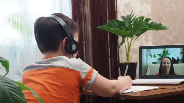 Akıllı bir çocuk masada oturuyor, ödev yazıyor ya da sınava hazırlanıyor. Çalışmak için dizüstü bilgisayar kullanan bir genç. Öğrenci, Okul, Uzaktan Öğrenme, Çevrimiçi Öğrenme, Yeni Normal, Ev Bazlı Öğrenme. — Stok video