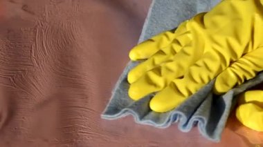 Kauçuk koruyucu sarı eldivenlerle beyaz yüzeyi bir bezle temizleyin. Ev, temizlik konsepti