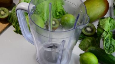 Ispanak, salatalık ve buz karıştıran bir kadın sağlıklı yeşil meyve suyu yapmak için. Kadın blenderdan bardağa yeşil detoks suyu döküyor..