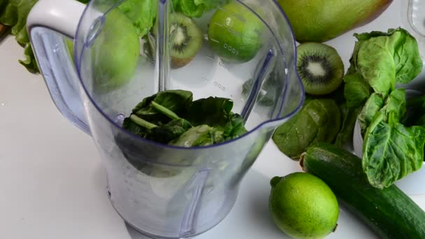 Mujer que mezcla espinacas, pepino, hielo para hacer un batido verde saludable. Mujer que vierte un jugo verde de desintoxicación de la licuadora a un vaso. — Vídeo de stock