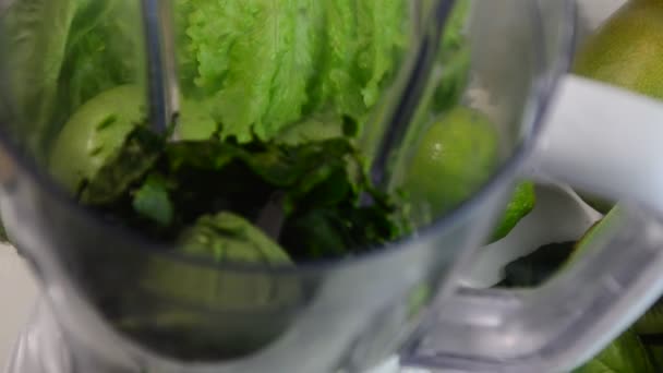 Kvinde blanding spinat, agurk, is til at gøre en sund grøn smoothie. Kvinde hælde en grøn detox juice fra blender til et glas. – Stock-video