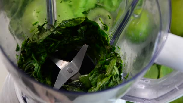 Женщина смешивает шпинат, огурец, лед, чтобы сделать здоровый зеленый смузи. Женщина наливает зеленый детоксикационный сок из блендера в стакан. — стоковое видео