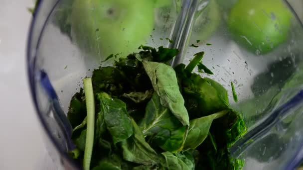 Mujer que mezcla espinacas, pepino, hielo para hacer un batido verde saludable. Mujer que vierte un jugo verde de desintoxicación de la licuadora a un vaso. — Vídeo de stock