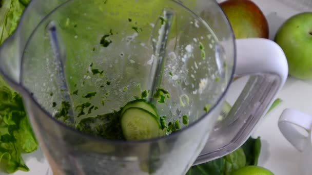 Mujer que mezcla espinacas, pepino, hielo para hacer un batido verde saludable. Mujer que vierte un jugo verde de desintoxicación de la licuadora a un vaso. — Vídeo de stock