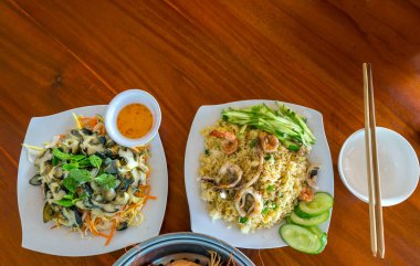 Masadaki deniz ürünleri tabakları arasında kızarmış pilav, salyangoz salatası, deniz ürünleri restoranında buğulanmış karides yer alıyor. İnsan beslenmesini teşvik et