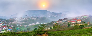 Vietnam 'ın Da Lat şehrinde, güneş doğarken gökyüzünde, bir çay tepesi vadisinde küçük bir köy. Burası tüm ülkeye büyük miktarda çay sağlıyor.