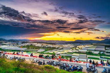 Da Lat, Vietnam - May 4th, 2021: Sunset landscape in agricultural greenhouse valley attracts tourists to roadside coffee for sightseeing, relaxing at the end of day in Da Lat plateau, Vietnam