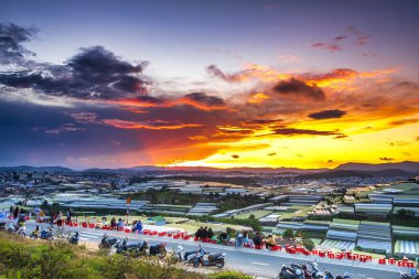 Da Lat, Vietnam - May 4th, 2021: Sunset landscape in agricultural greenhouse valley attracts tourists to roadside coffee for sightseeing, relaxing at the end of day in Da Lat plateau, Vietnam
