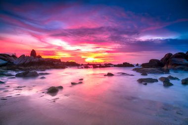 Beautiful sunrise on the beach below the waves lapping at the shore of the soft great to welcome the peaceful new day