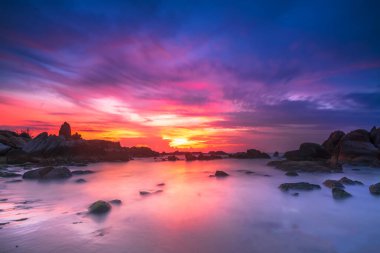 Beautiful sunrise on the beach below the waves lapping at the shore of the soft great to welcome the peaceful new day