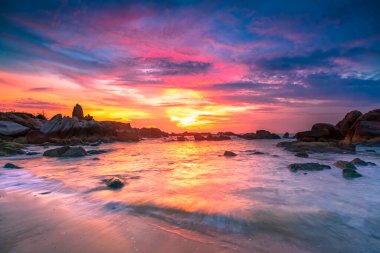 Beautiful sunrise on the beach below the waves lapping at the shore of the soft great to welcome the peaceful new day