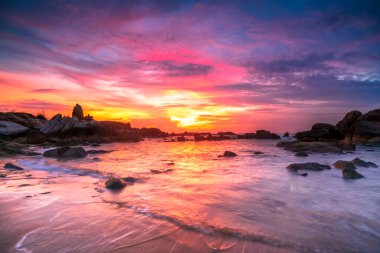 Beautiful sunrise on the beach below the waves lapping at the shore of the soft great to welcome the peaceful new day