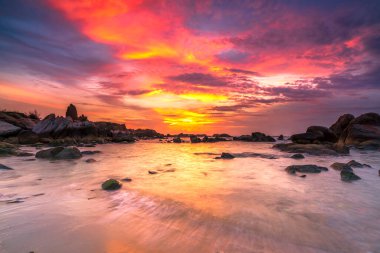 Beautiful sunrise on the beach below the waves lapping at the shore of the soft great to welcome the peaceful new day