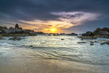 Beautiful sunrise on the beach below the waves lapping at the shore of the soft great to welcome the peaceful new day