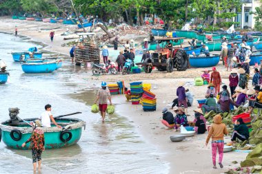 Phan Thiet, Vietnam - May 6th, 2021: Fish market session seas scene people gathered inside basket fish sale, strenuous rowing fishermen brought ashore fishing village in Phan Thiet, Vietnam