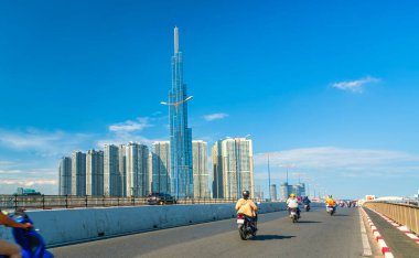 Ho Chi Minh şehri, Vietnam, 27 Şubat 2021: Nehir kenarındaki yüksek kentsel alanın yanındaki köprüdeki trafik, Ho Chi Minh şehrindeki refah ekonomik kalkınmayı temsil ediyor