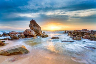 Güneşin doğuşu güzel kumsalın kayalık sahillerinde