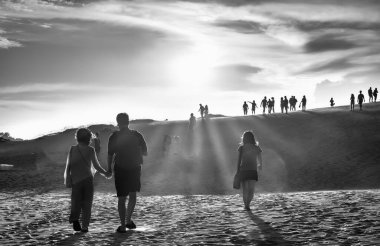 Sahilde yürüyen bir grup insan.