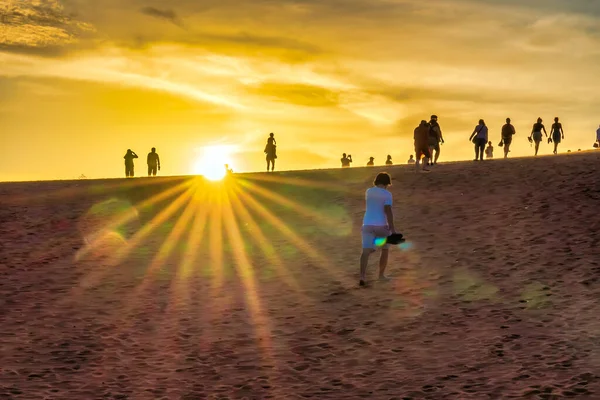 İnsanlar gün batımında sahilde.