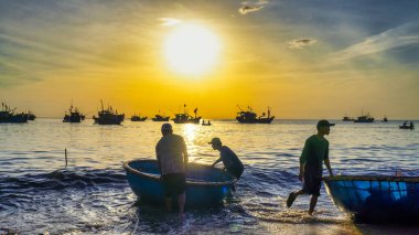 Akşam vakti sahildeki insanların silueti.