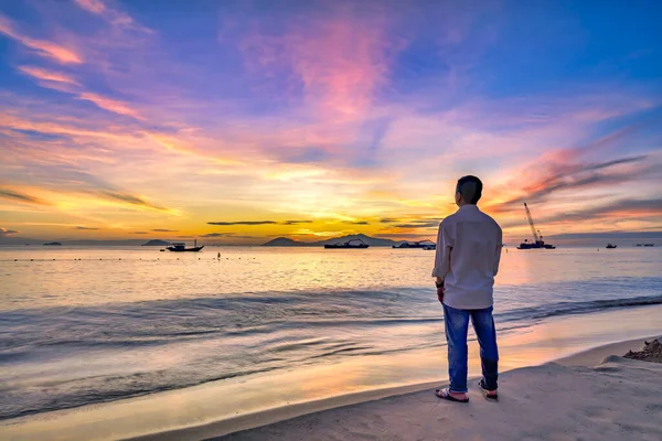 Sahilde gün batımlı genç adam