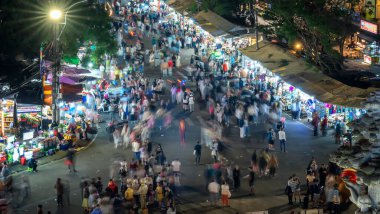 Şehirdeki gece pazarında yürüyen insanlar.