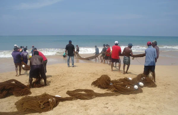 INDURUWA, SRI LANKA - 22 MAR 2014: Sri Lankan fishermen pull big net in Induruwa, Sri Lanka. — Stock Photo, Image