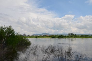 Bu resim tepeli bir nehri ve şehir manzaralı bir sahili gösteriyor.