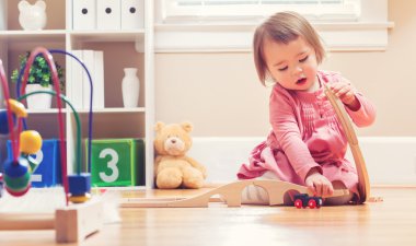 Oyuncakları ile oynarken mutlu yürümeye başlayan çocuk kız
