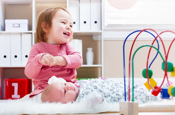 Šťastná dívka si hraje s její sourozenec dítěte — Stock fotografie