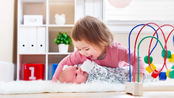 Šťastná dívka si hraje s její sourozenec dítěte — Stock fotografie