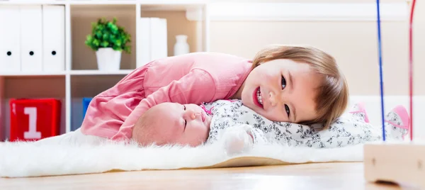 Menina feliz brincando com seu irmão bebê — Fotografia de Stock