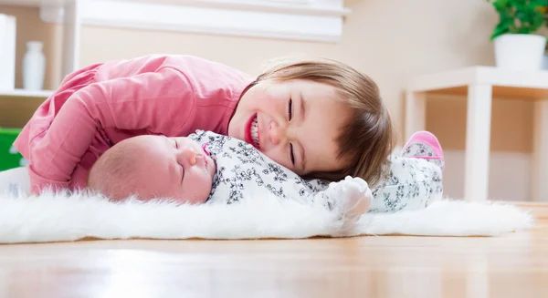 Šťastná dívka si hraje s její sourozenec dítěte — Stock fotografie
